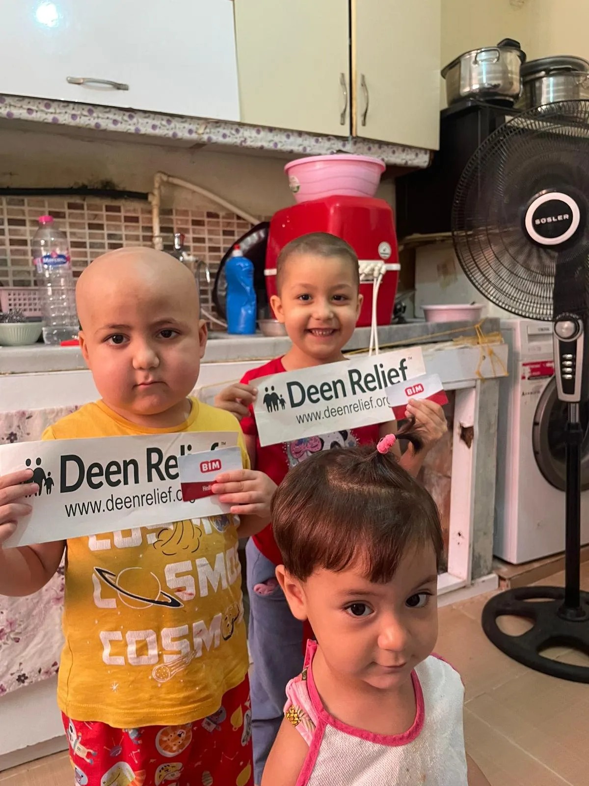 Syrian children with cancer holding Deen Relief signs and smiling