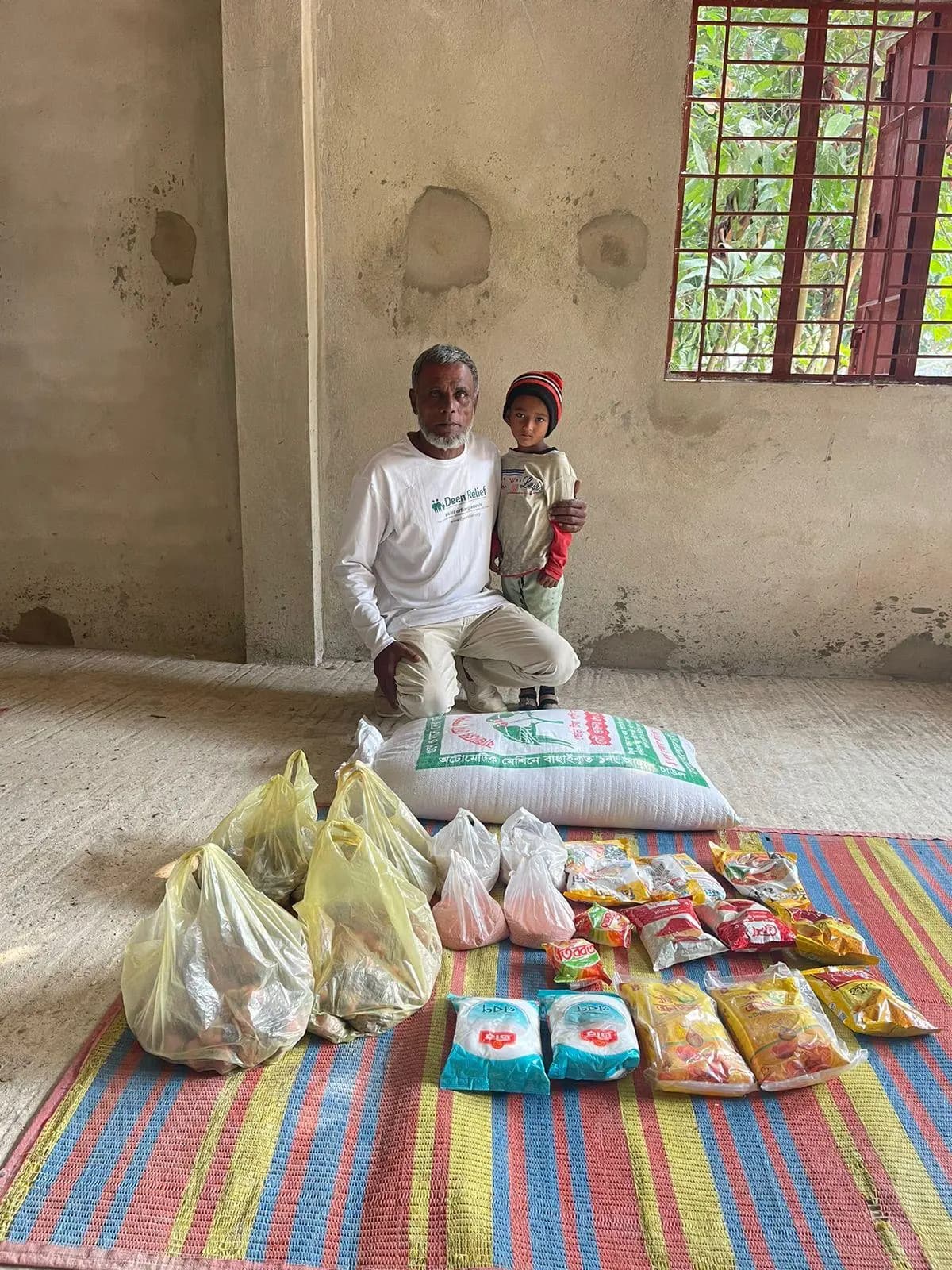 Deen Relief team member with a sponsored child and food supplies in Bangladesh